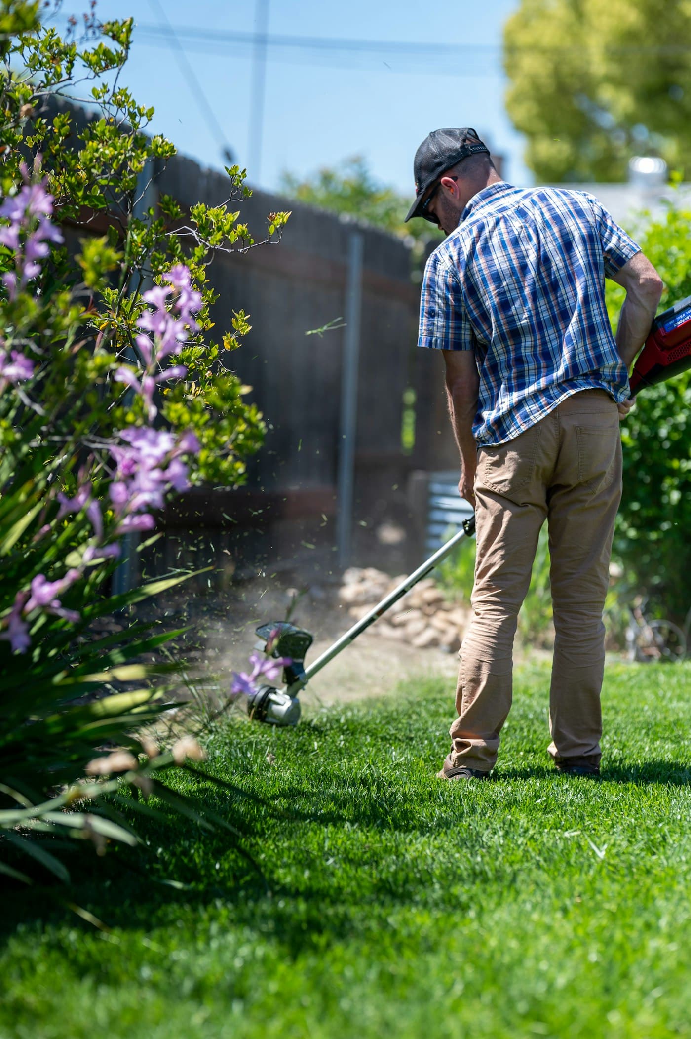 String trimmer edging a lawn by a flower bed